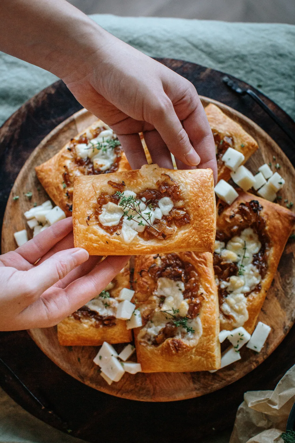 Zapečen tart iz listnatega testa, obložen s karamelizirano šalotko, kozjim sirom in svežim timijanom.